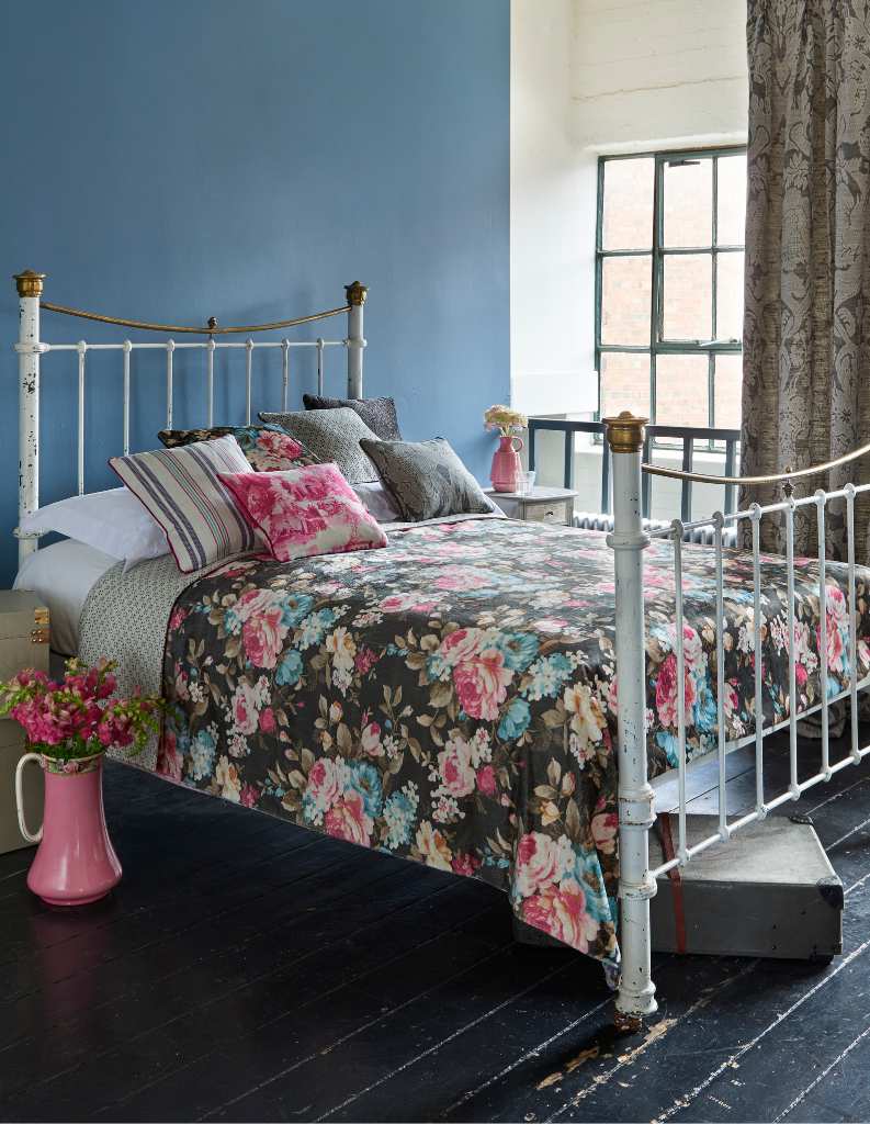 A colourful chintz bedroom with patterned curtains and floral bedding. 