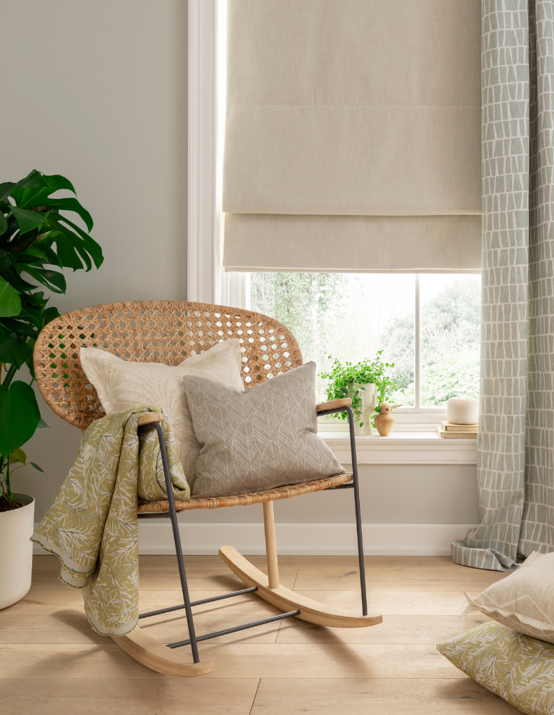 Cosy neutral Roman blinds in a window layers with patterned curtains. 