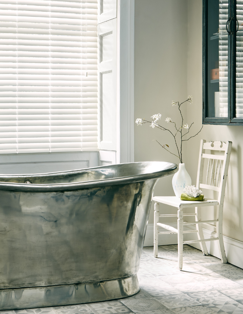 White shutter blinds in bathroom with metal tub.