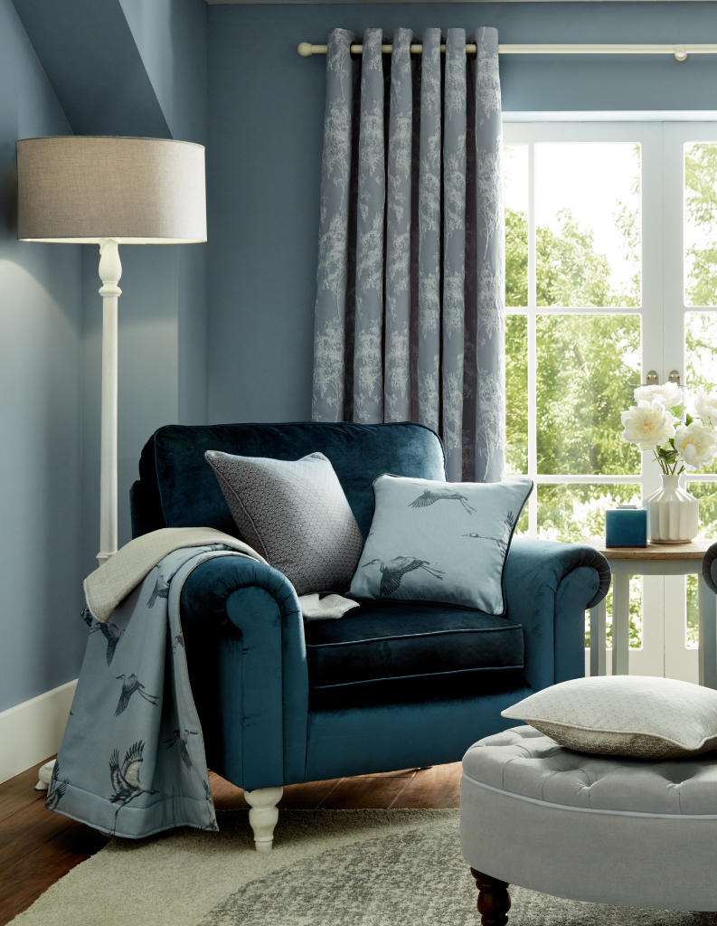 A sky blue sitting area with a rich teal coloured armchair. 
