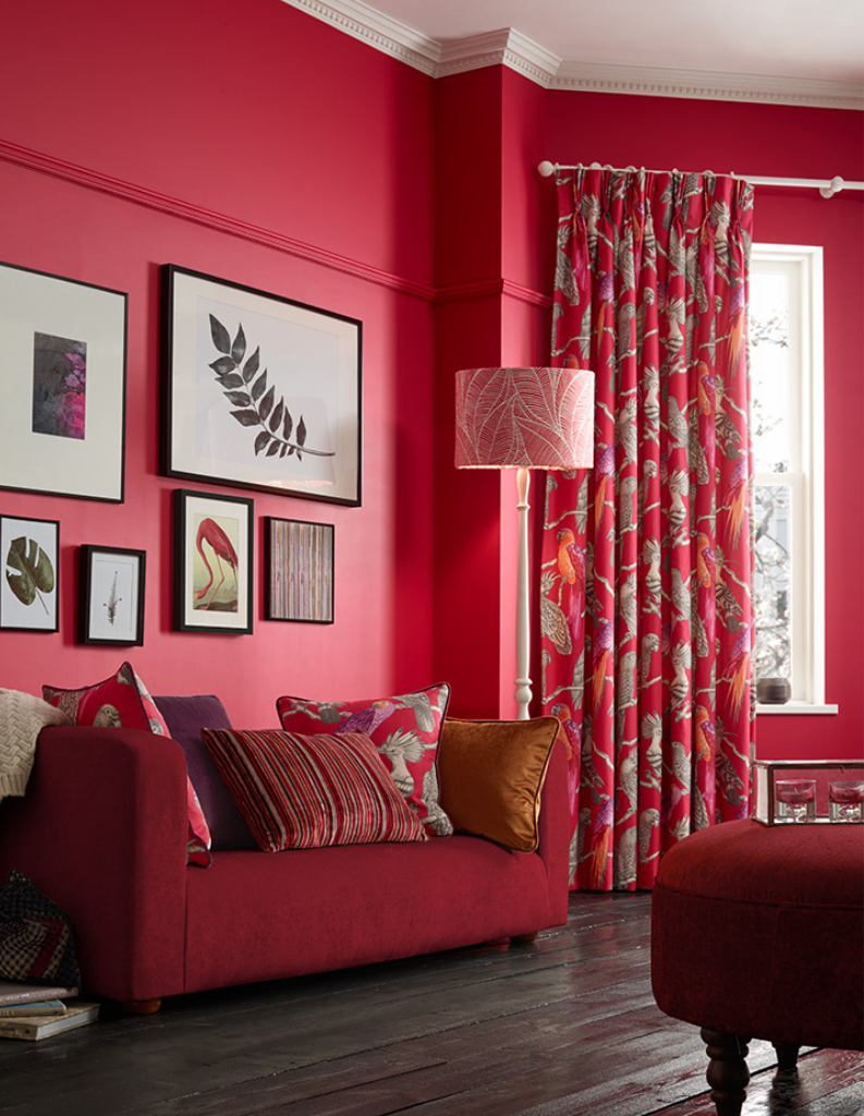 A cherry red living room with red patterned curtains and a rich red sofa. 