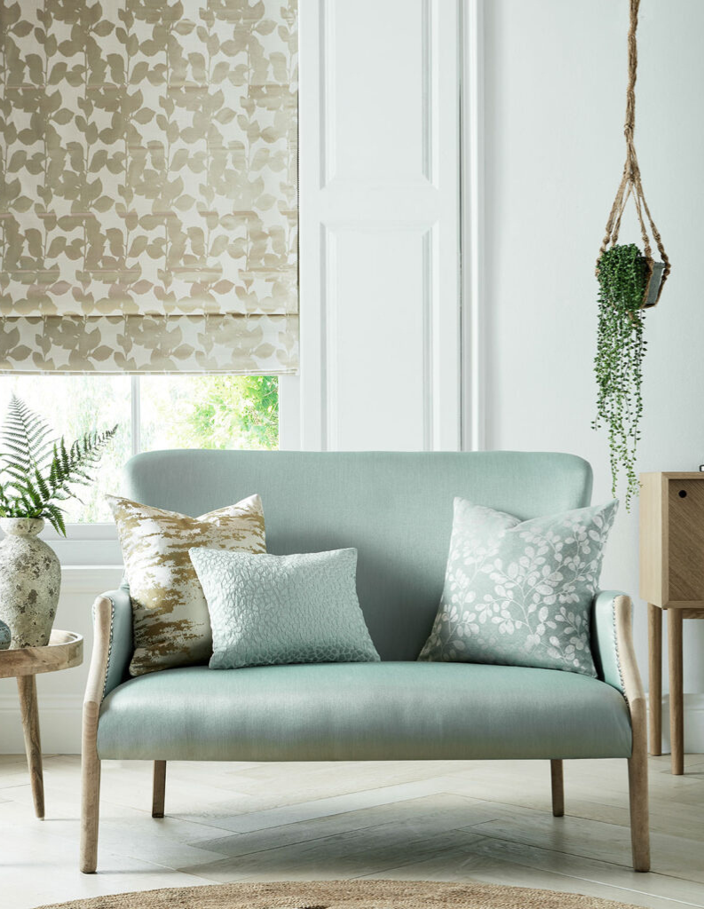 A classical living room with pale blue sofa and patterned Roman blinds.
