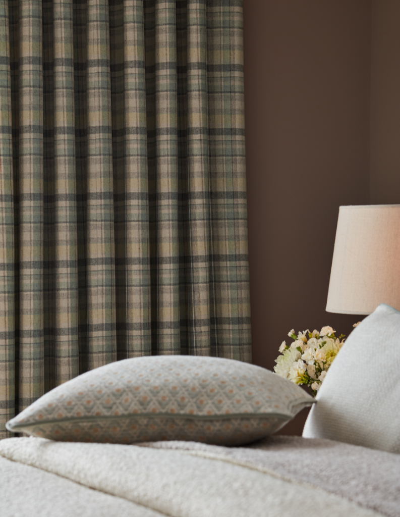 A country cabin bedroom featuring floral cushions and checked curtain. 
